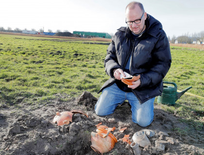 Archeoloog John van Lunsen bekijkt het gevonden aardewerk